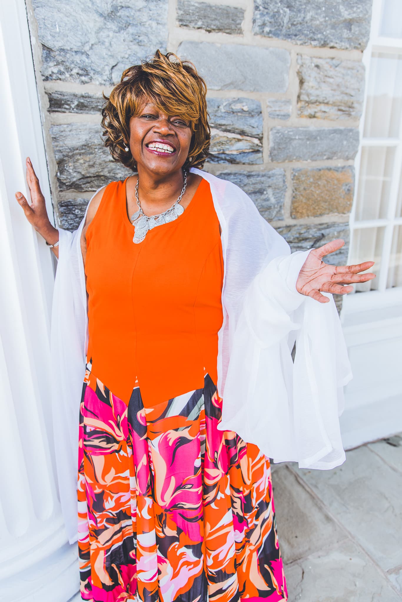 Jennifer Harris laughing, in a bright orange dress